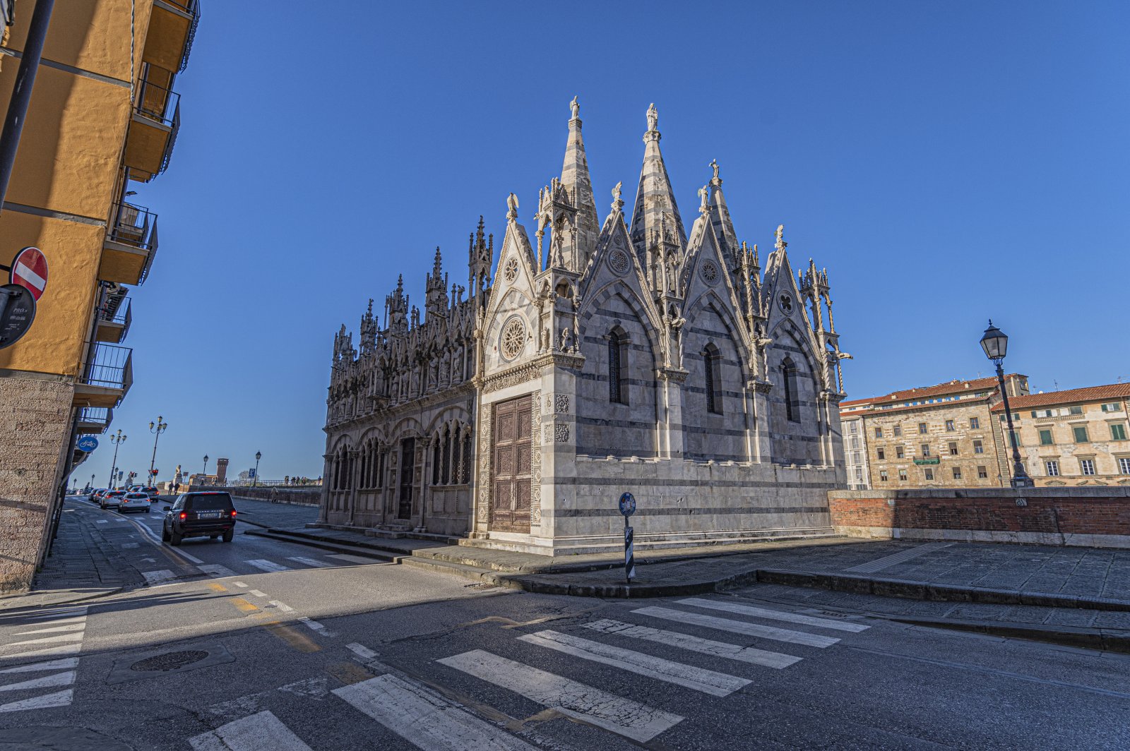 Opierając się na parapecie Lungarno Gambacorti, z widokiem na rzekę w punkcie f - Pisa | Secret World Trip Planner